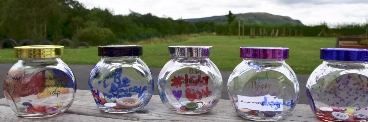 Row of glass jars containing buttons